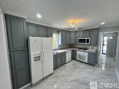 A kitchen with a white refrigerator and grey cabinets.