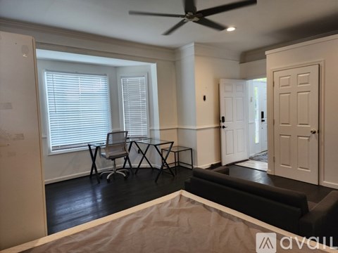 A living room with a black couch and a fan on the ceiling.
