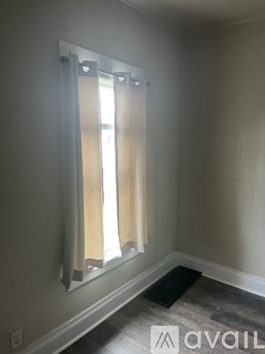 A room with a mirror and a window with curtains.