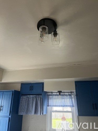 A kitchen with blue cabinets and a window with a curtain.