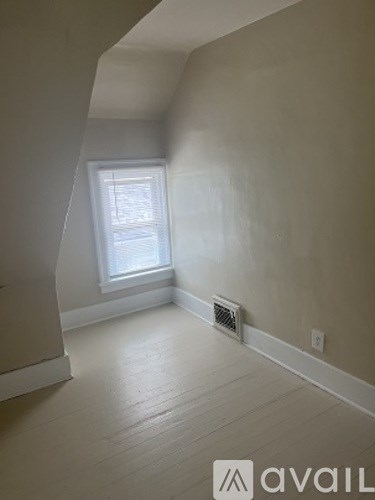 A room with a window and a vent on the wall.