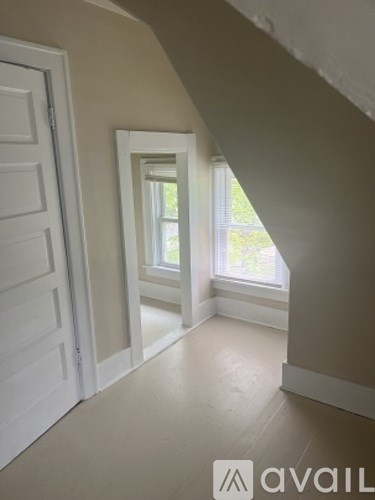 A hallway with a white door and a window.