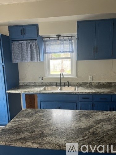 A kitchen with blue cabinets and a marble countertop.