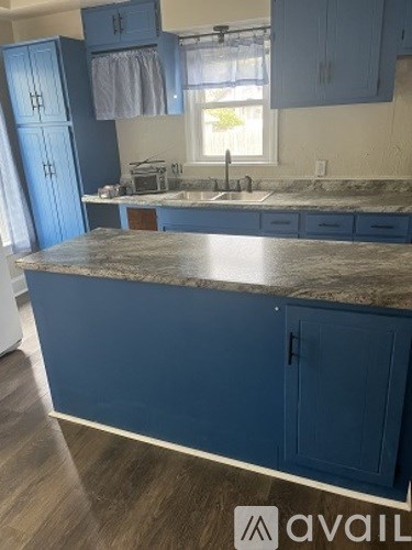 A kitchen with blue cabinets and a marble countertop.