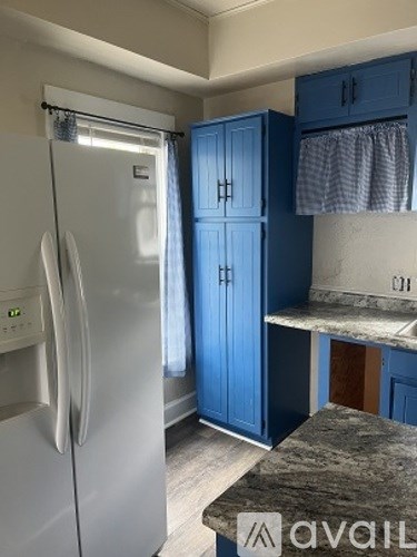 A kitchen with a white refrigerator and blue cabinets.