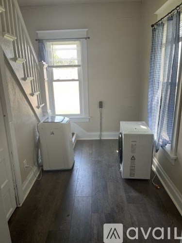 A room with a staircase on the left and two white appliances on the right.