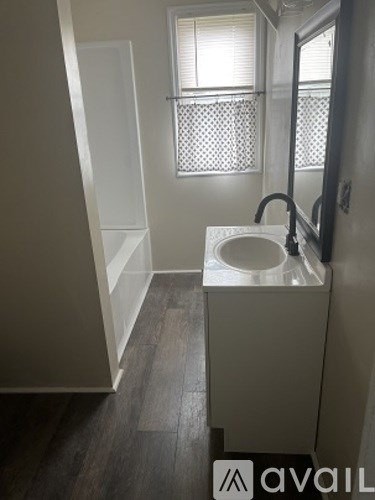 A bathroom with a toilet, sink, and a window with a curtain.
