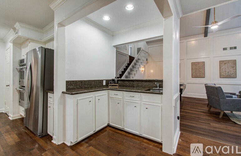 A kitchen with white cabinets and a stainless steel refrigerator.