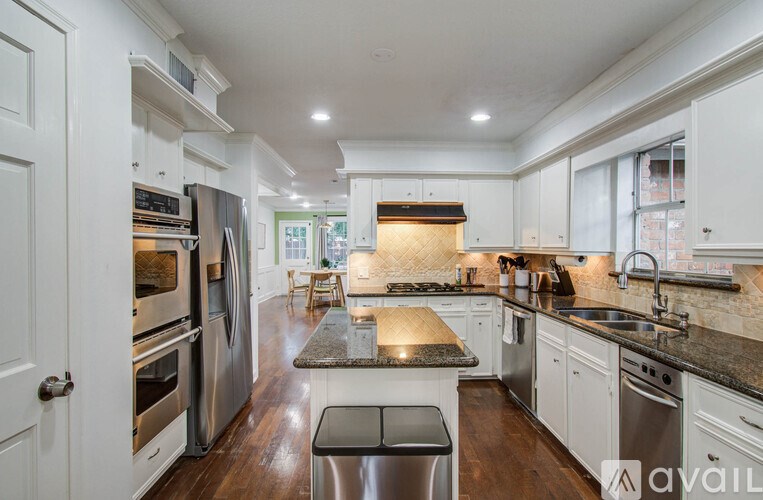 A modern kitchen with white cabinets and stainless steel appliances.