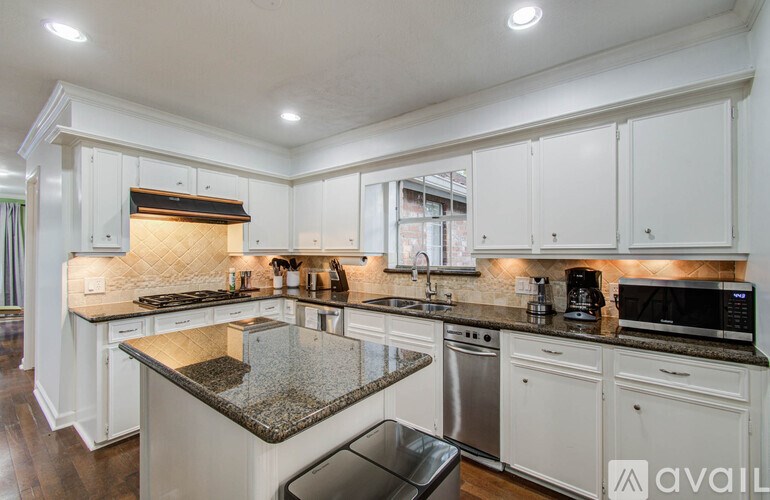 A kitchen with white cabinets and a granite countertop.