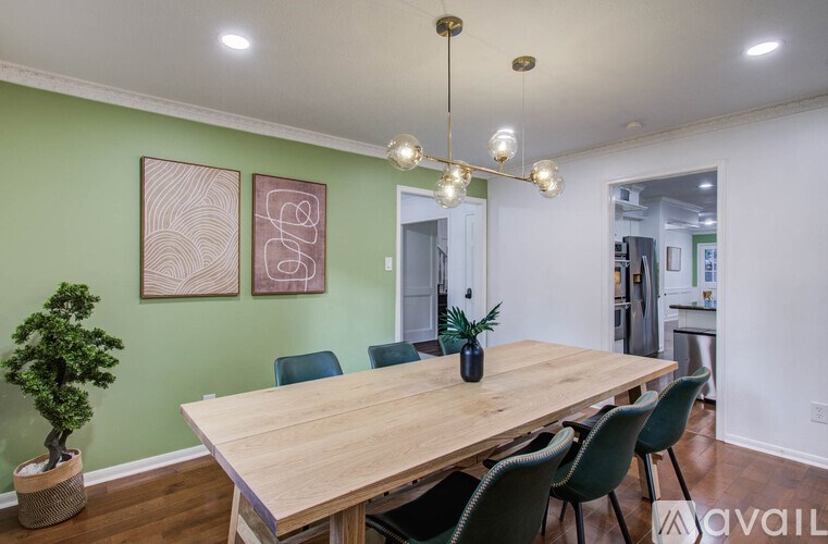 A dining room with a wooden table and green chairs.