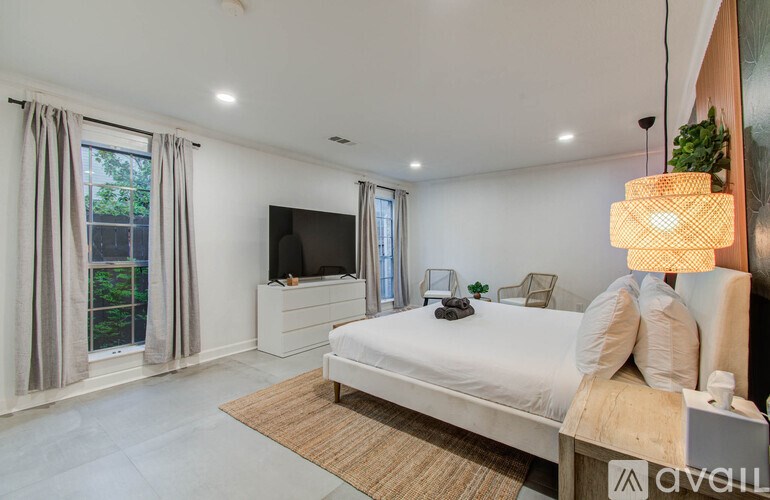 A bedroom with a large bed, a television, and a window with curtains.