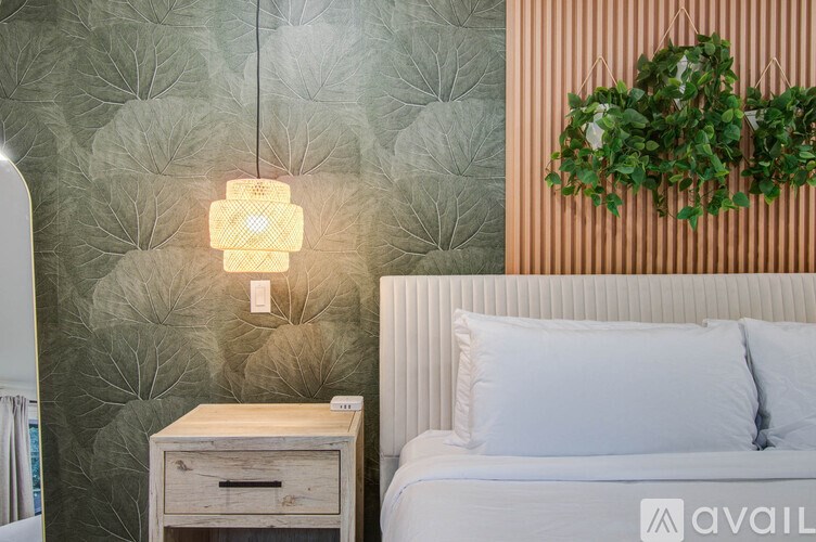 A bedroom with a white bed and a wall with leaf patterns.