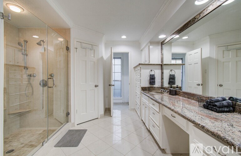 A bathroom with a walk-in shower and a vanity with a marble countertop.