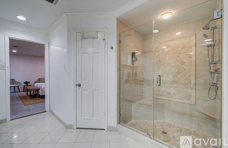 A bathroom with a walk-in shower and a doorway leading to a dining area.