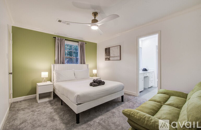A bedroom with a white bed and a green couch.