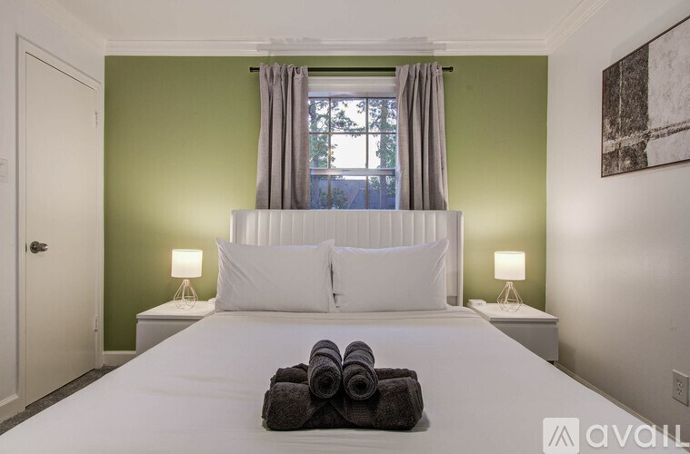 A bedroom with a large bed and two lamps.