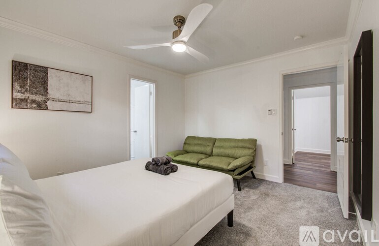 A bedroom with a bed, green sofa, and a ceiling fan.