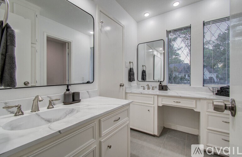 A bathroom with a white vanity and a large mirror.