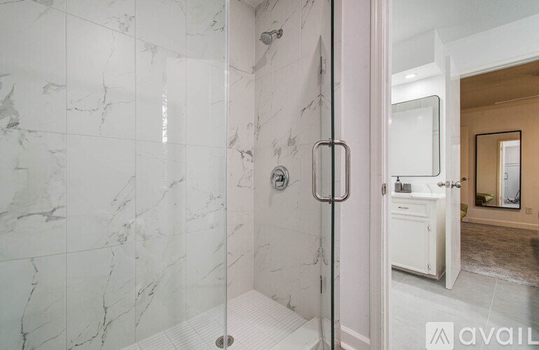 A bathroom with a marble tile shower and a white door.