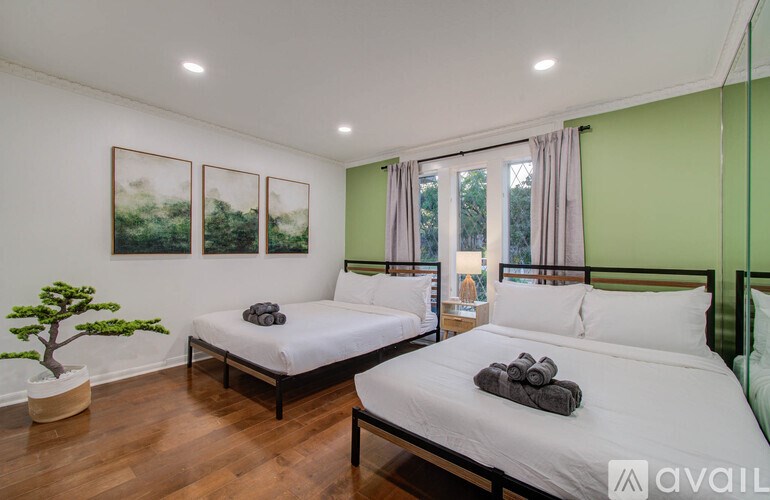 A bedroom with two beds and a small tree.