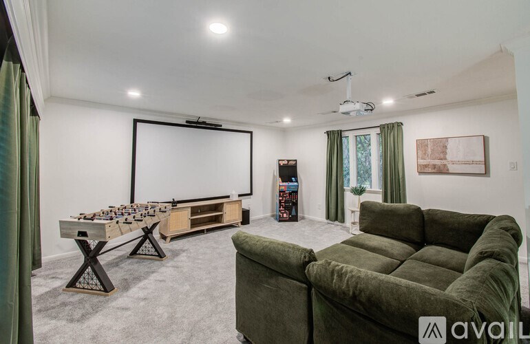 A room with a green couch, a table, a chess set, and a projector screen.