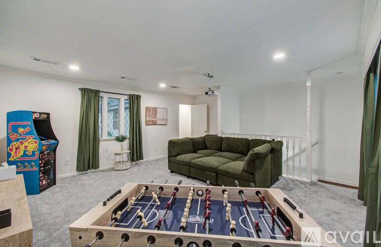 A foosball table is in the middle of a room with a green couch.