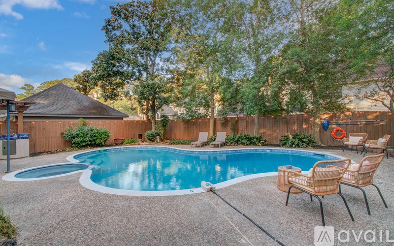 A pool surrounded by a concrete patio and a wooden fence.