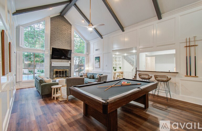 A billiard table is in the middle of a room with a fireplace and a couch.