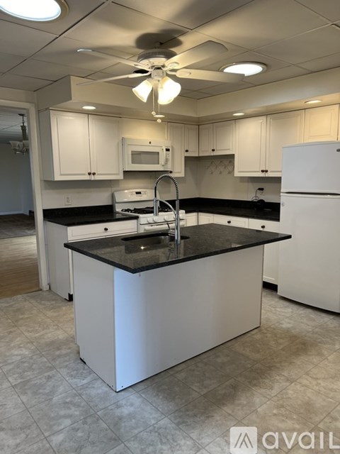 A kitchen with white cabinets and a black countertop.