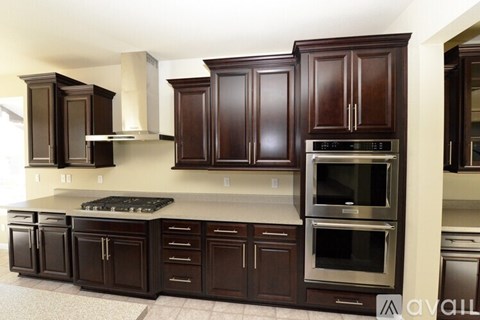 A kitchen with dark wood cabinets and stainless steel appliances.