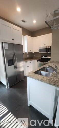 A kitchen with white cabinets and a granite countertop.