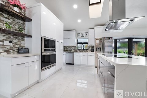 A modern kitchen with white cabinets and a stone wall.