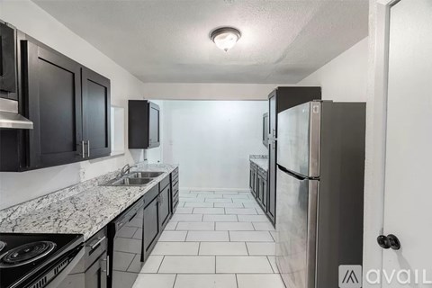 A kitchen with black cabinets and a granite countertop.