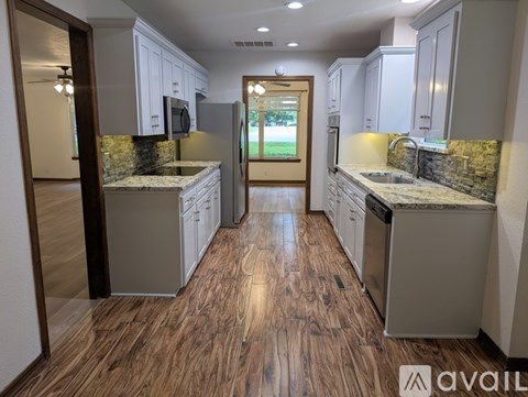 A kitchen with wood flooring and granite countertops.