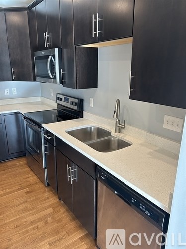 A kitchen with black cabinets and a stainless steel dishwasher.