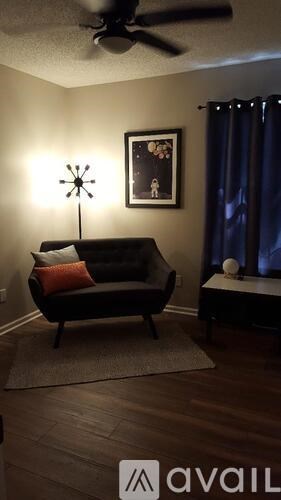 A living room with a black couch and a ceiling fan.