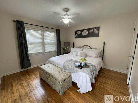 A bedroom with a bed, bench, and a ceiling fan.