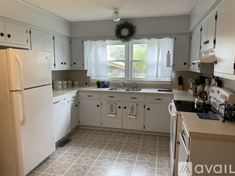 A kitchen with white appliances and cabinets.