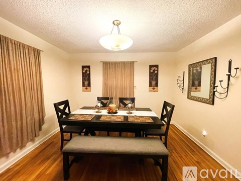 A dining room with a table set for two and a chandelier hanging from the ceiling.