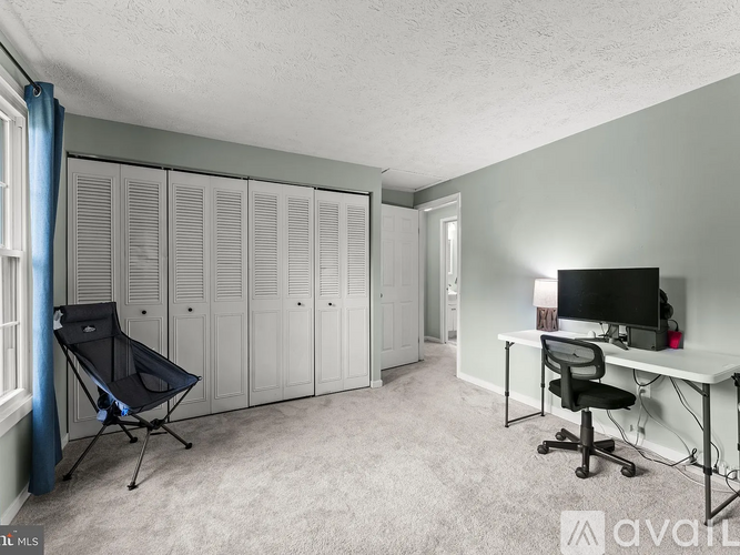 A room with a desk, chairs, and a computer setup.