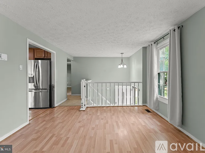 A spacious room with wooden flooring and a white railing.
