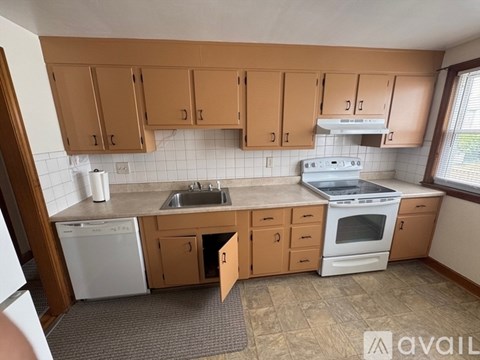 A kitchen with wooden cabinets and a white dishwasher.