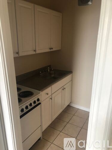 A kitchen with white cabinets and a stove top oven.