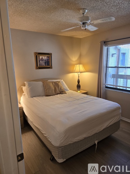 A bedroom with a bed, a ceiling fan, and a window.