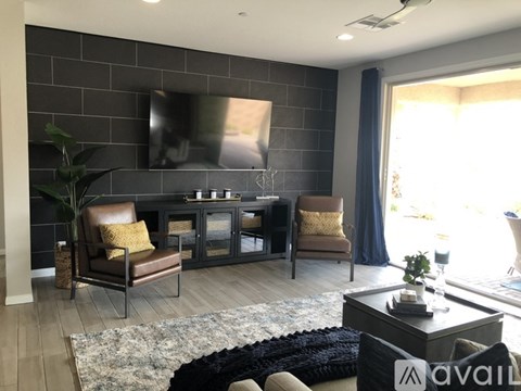 A living room with a black couch and a television on the wall.