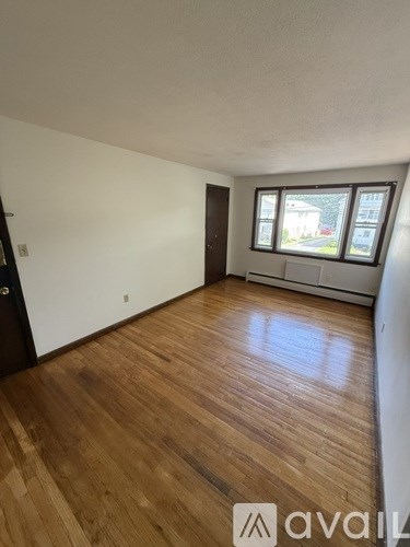 A room with wooden flooring and a window showing an outdoor view.