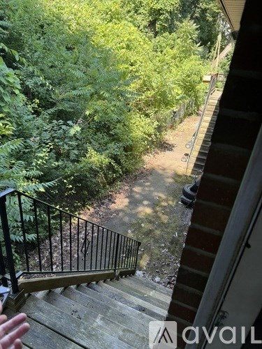 A staircase with a metal railing leads down to a wooded area.