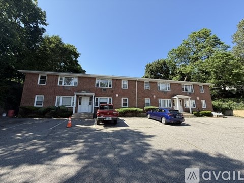 A parking lot in front of a brick building with a blue car parked.