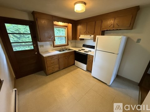 A kitchen with white appliances and wooden cabinets.